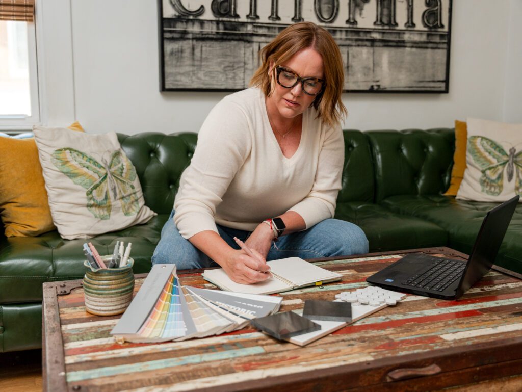 Courtney Murphy at home making notes on her coffee table with paint samples and finishes on the table.