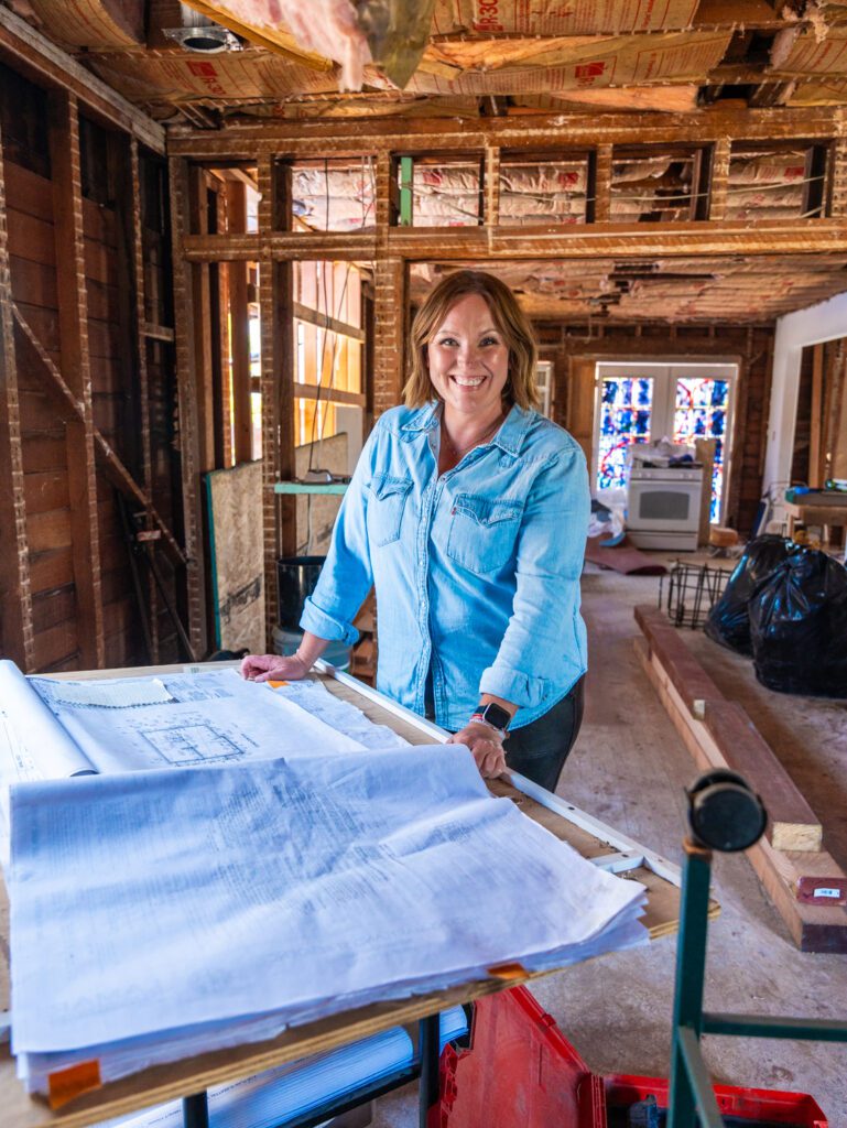 Courtney Murphy on a renovation jobsite under construction examining blueprints.