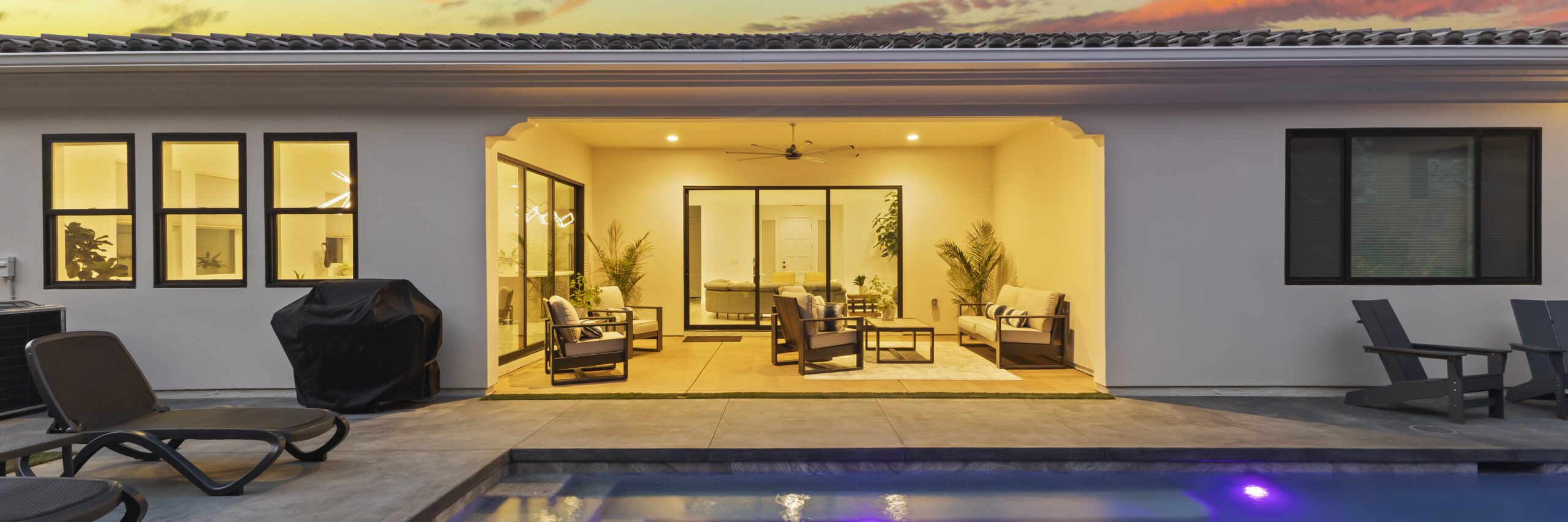 Modern home and backyard with pool shot at twilight. Glowing interior lights light up the inside of the home.