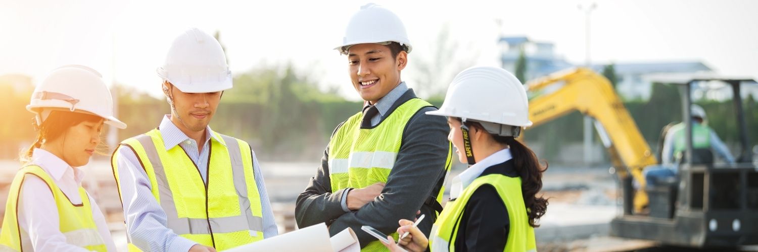 Group of architects looking at a blueprint on a jobsite.
