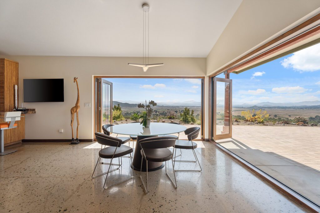 Open concept dining room with accordion doors folded back leading out to the backyard spaces.